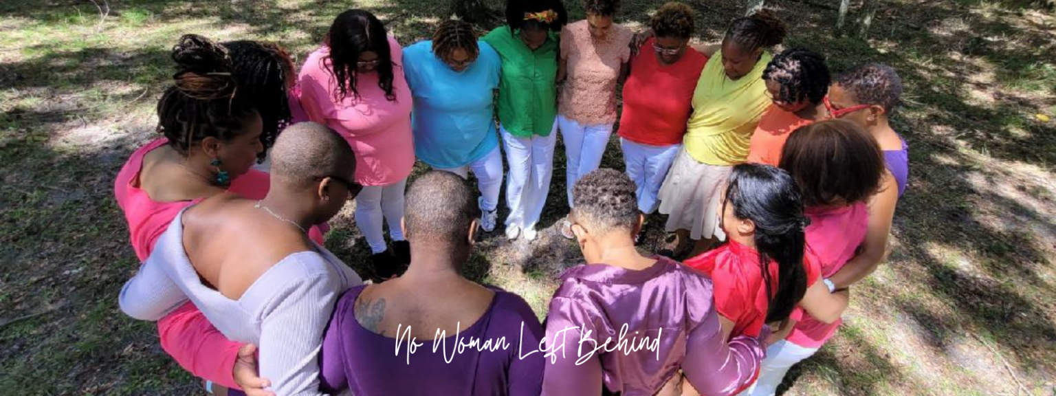 A circle of women outdoors with their arms around each other, heads bowed in prayer, with the words 'No Woman Left Behind' across the image