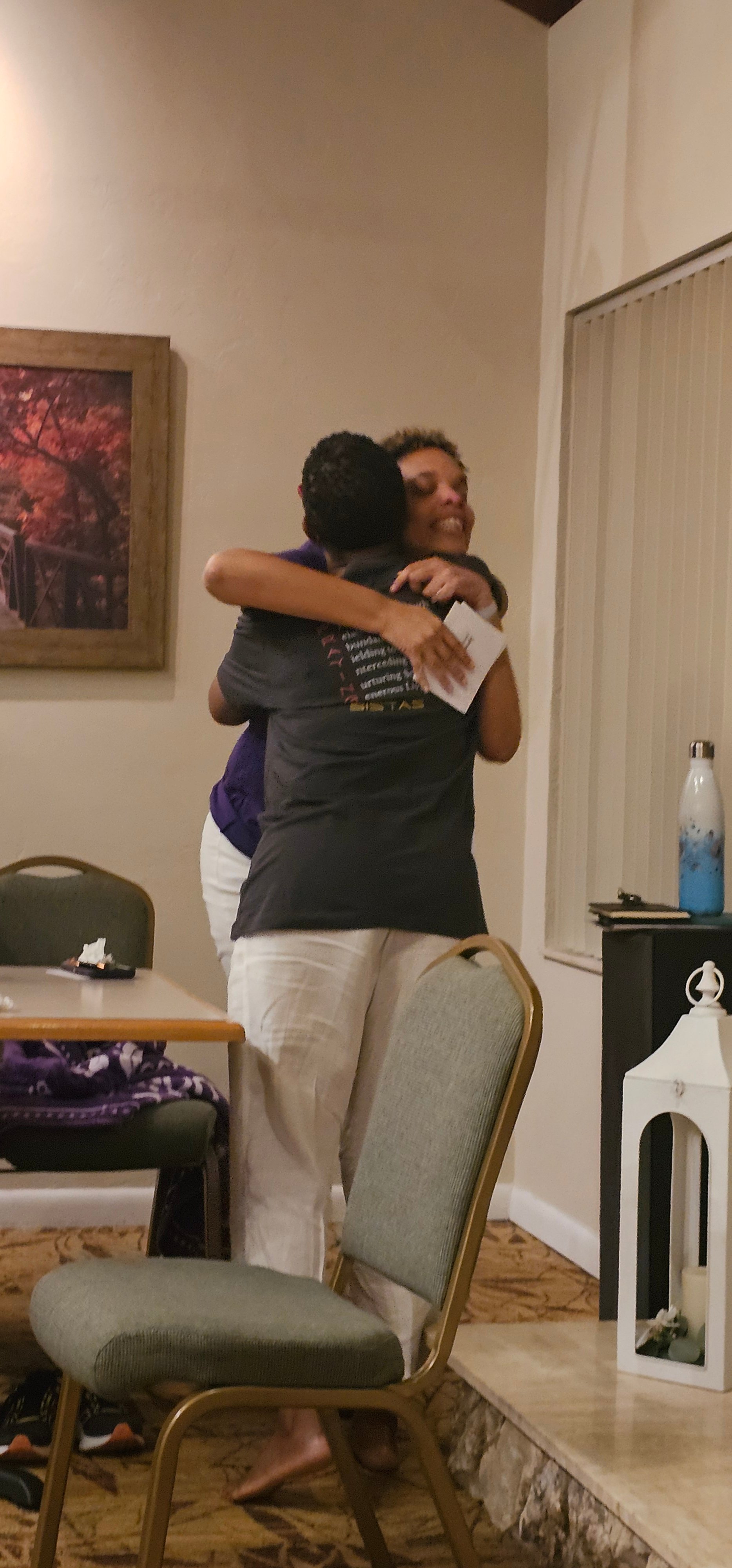 Two women hugging indoors and smiling